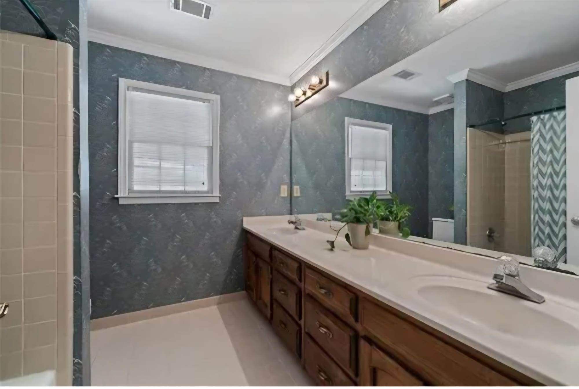 Bathroom with blue-gray textured wallpaper and a dark wood vanity, before renovation