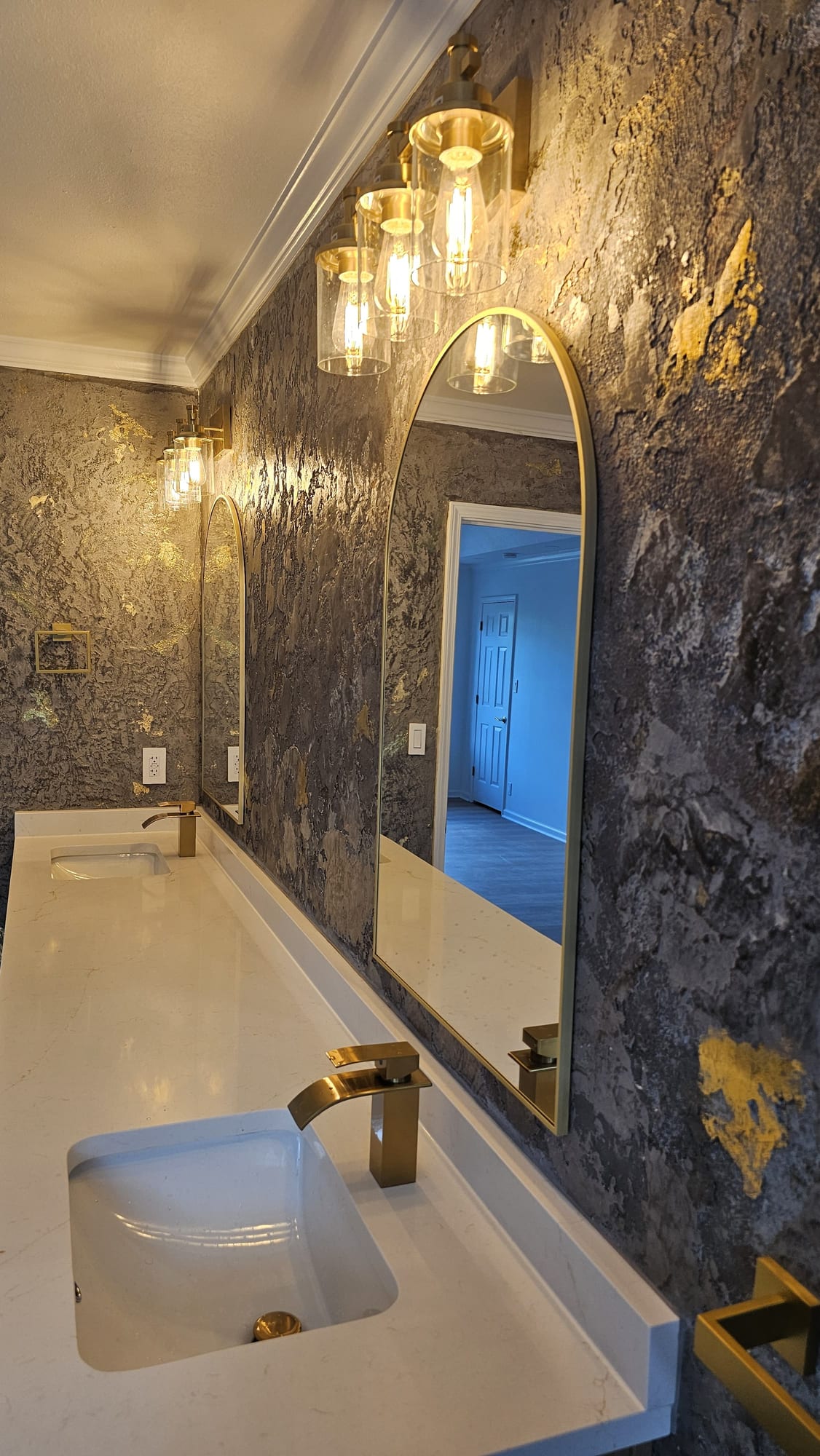 Bathroom with a textured Venetian plaster wall in a gold-leaf imitation stone finish, and a double vanity