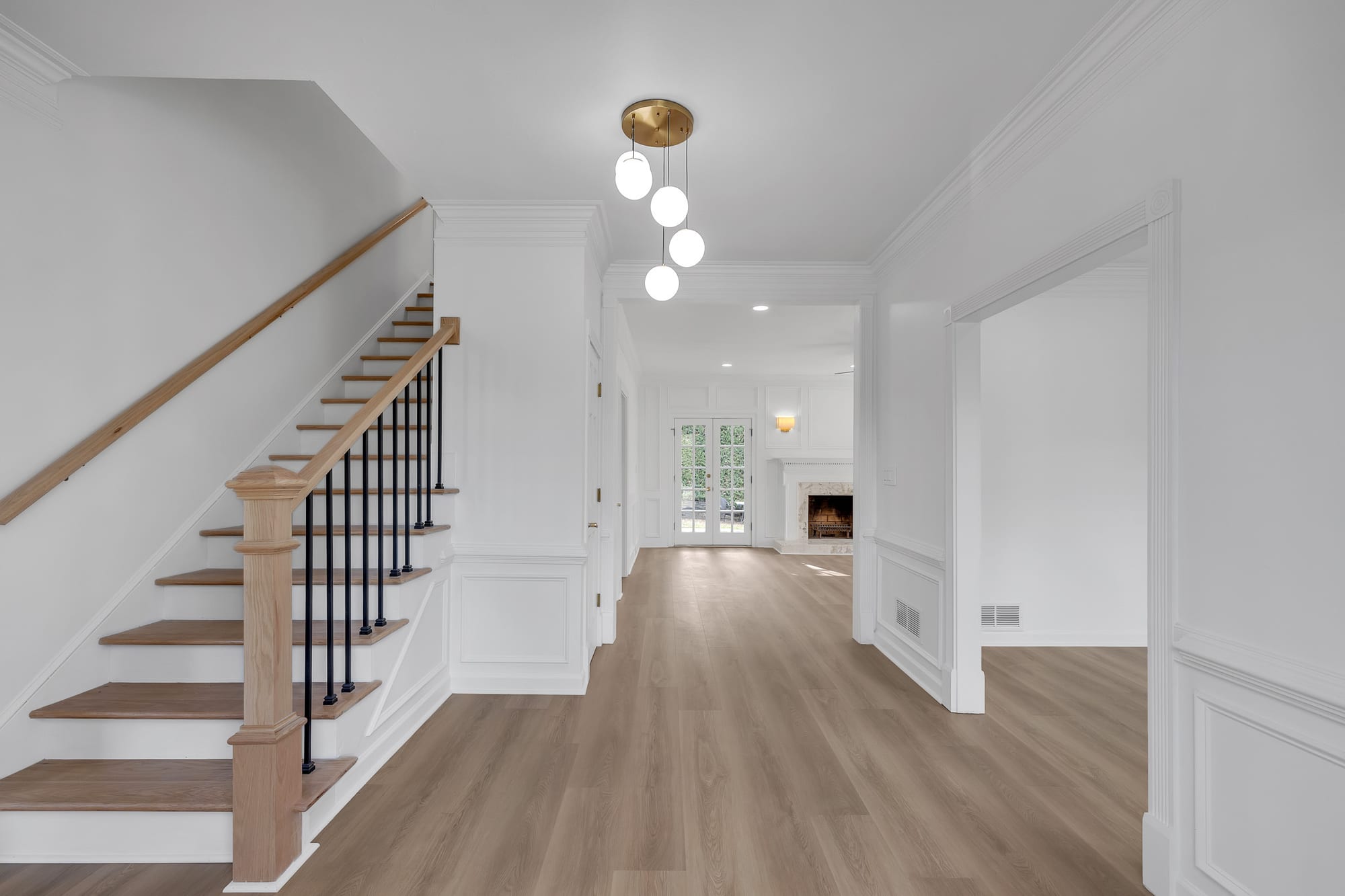 Entry hall with staircase, brass globe pendant light, and a view toward the fireplace