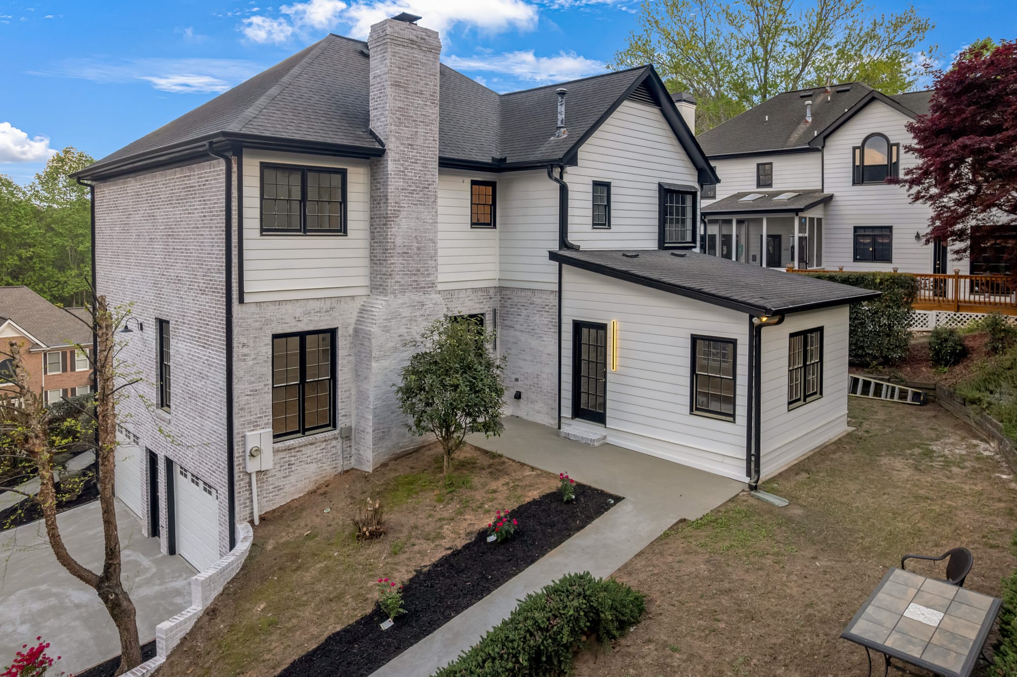Renovated home exterior with whitewashed brick, white siding, and black trim