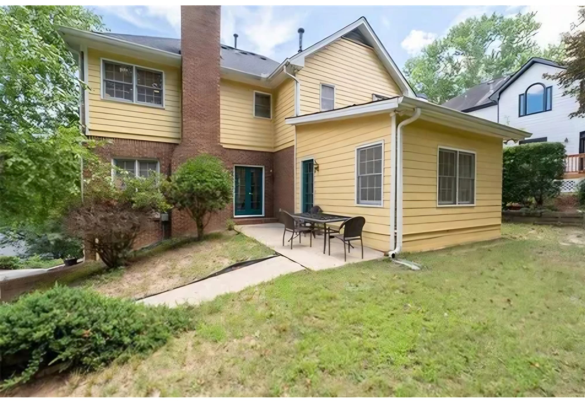 Home exterior with yellow siding and a brick lower level, before renovation
