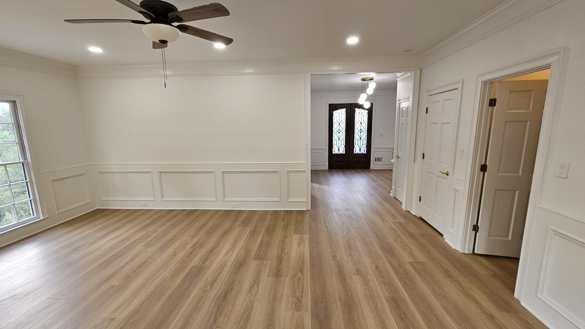 Foyer with a wrought iron and glass front door, white paneled doors, and a brass pendant light