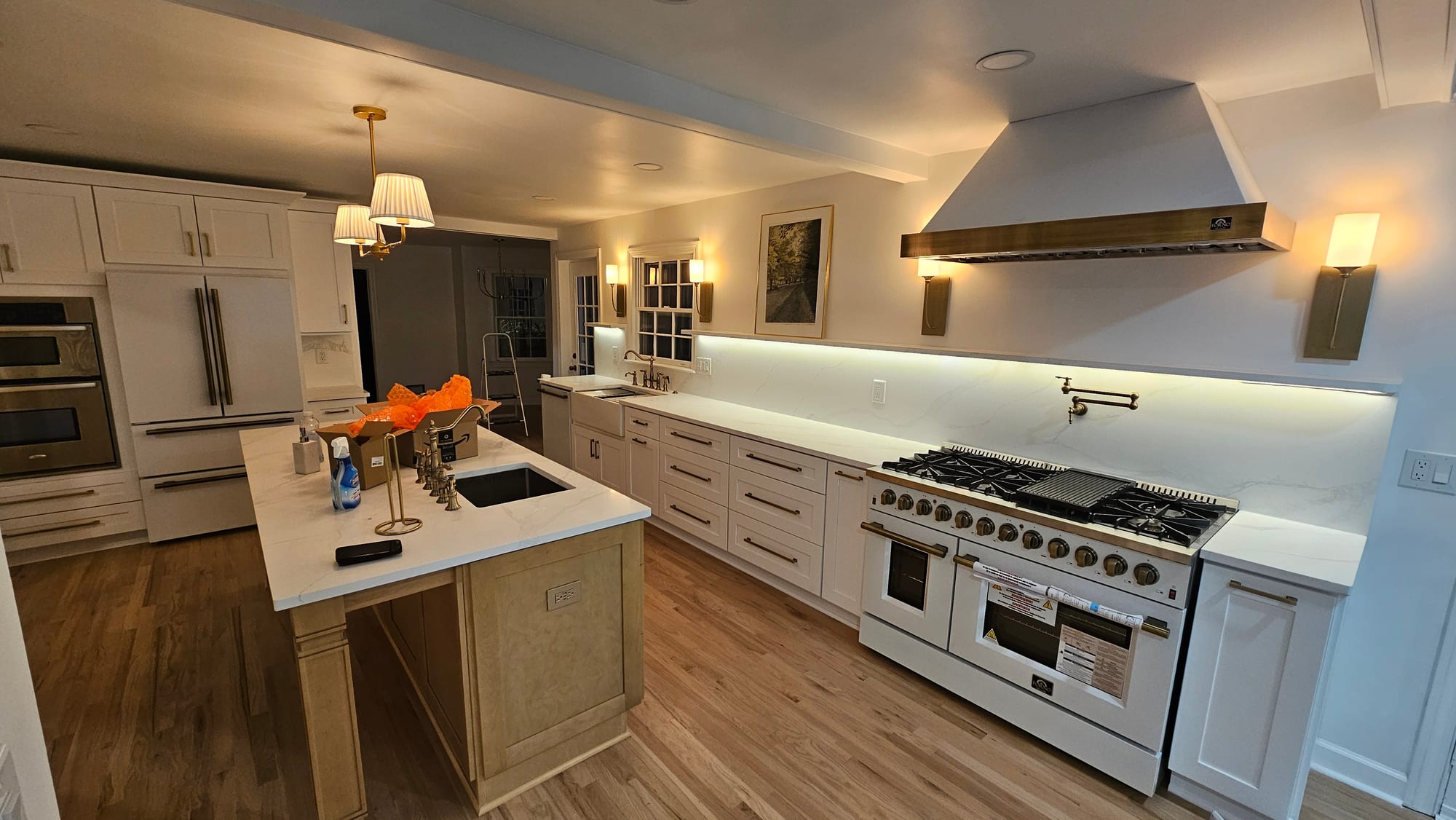 Renovated kitchen with a brass range hood, under-cabinet lighting, and a paneled refrigerator where the chimney chase once stood