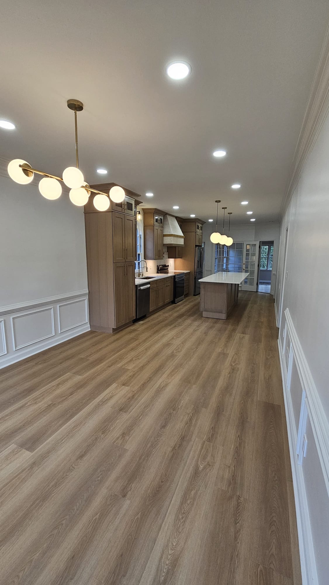 Kitchen and dining area beneath a brass multi-globe chandelier