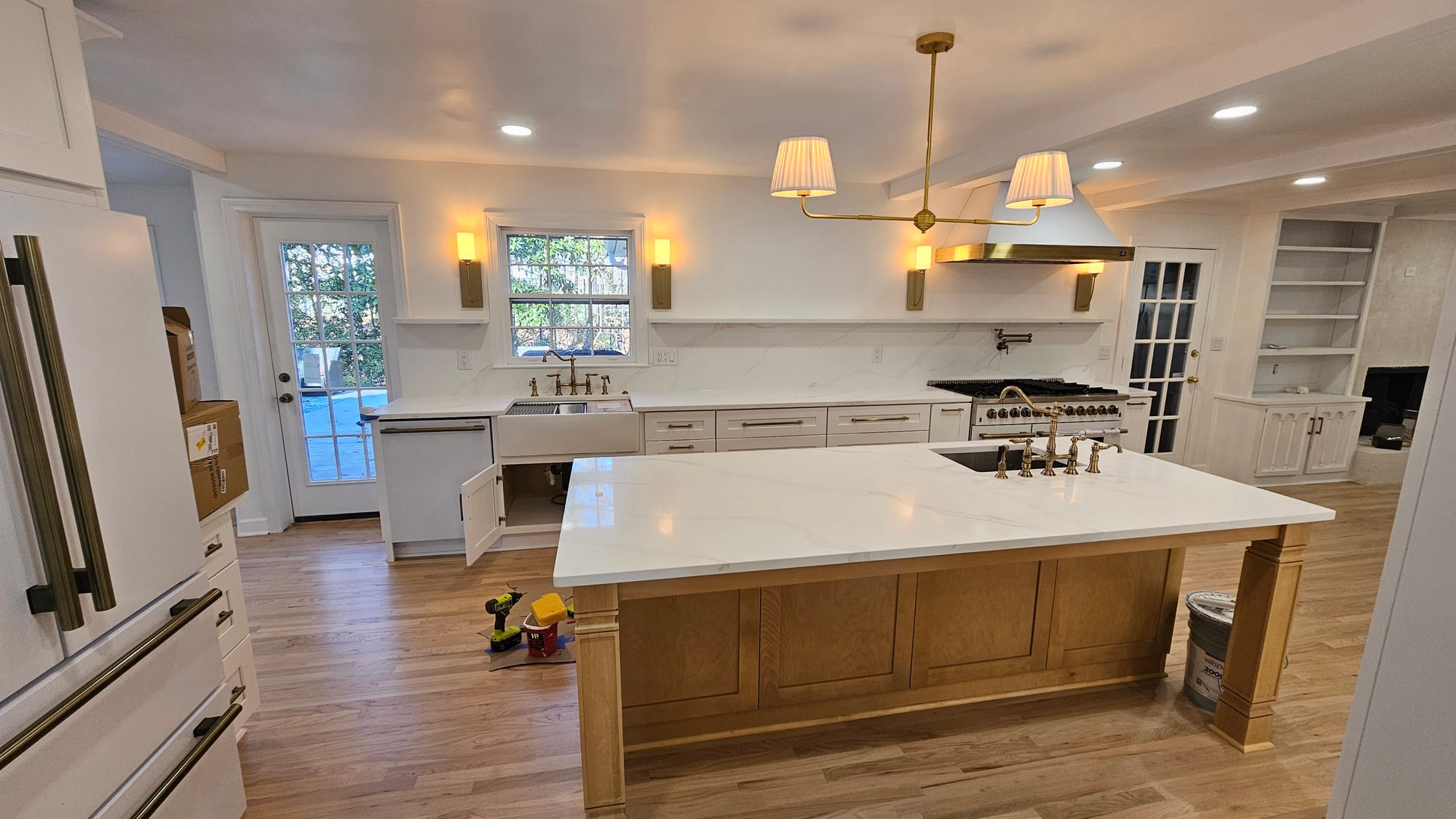 Renovated kitchen with a farmhouse sink beneath a window, brass chandelier, and French door