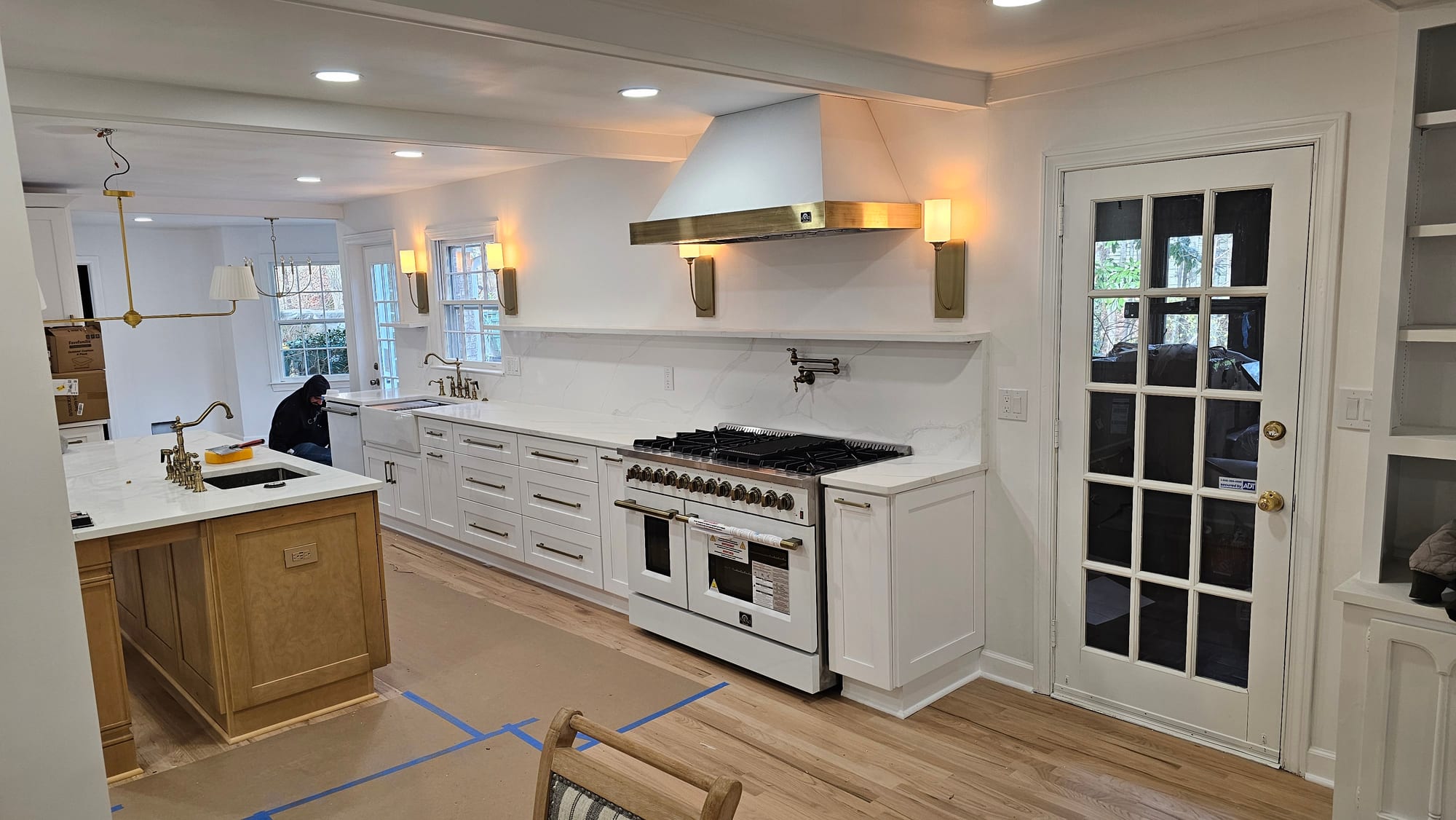 Renovated kitchen island with a brass range hood and a glass French door