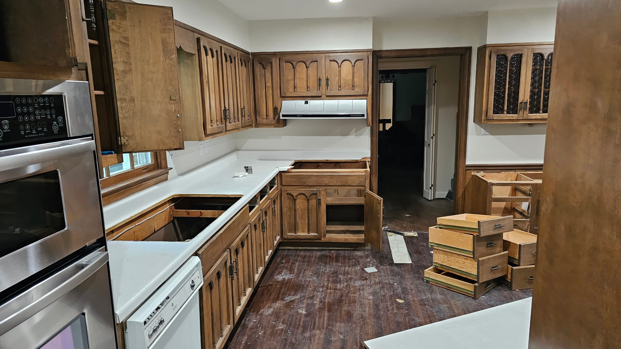 Kitchen with oak arched-panel cabinets, a wall-oven tower, and a window, before renovation