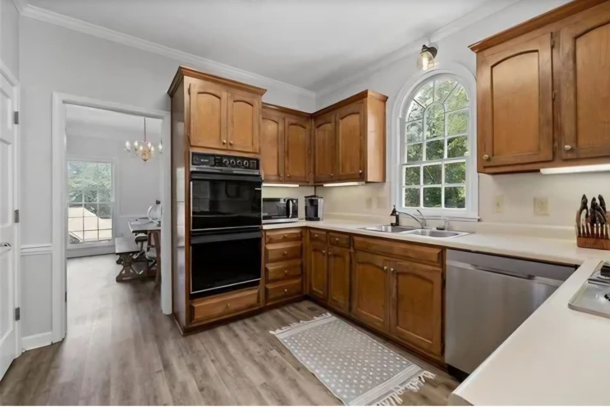Kitchen with oak cabinets and a black double wall oven, before renovation