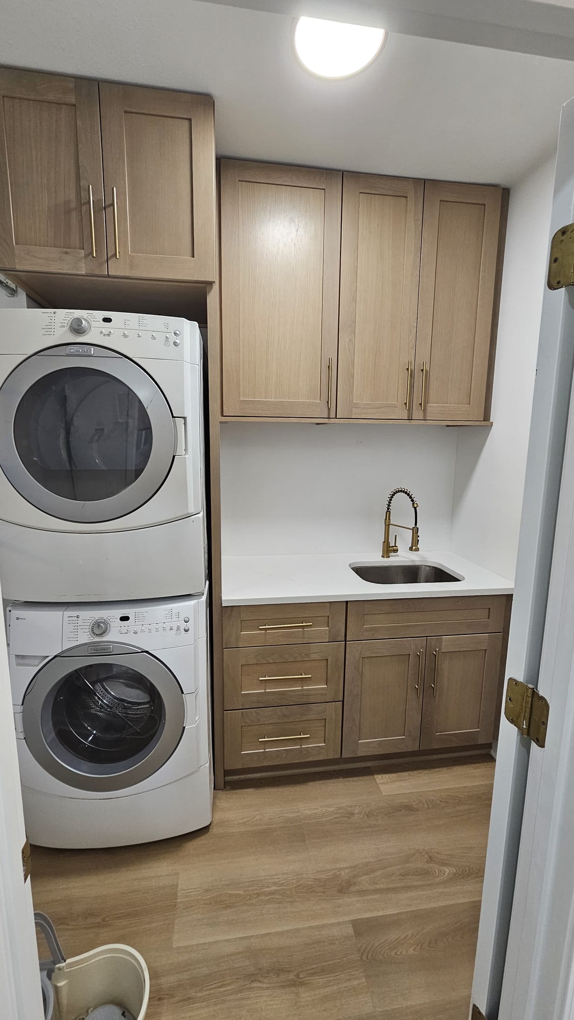 Laundry room with a stacked washer and dryer and a brass gooseneck faucet