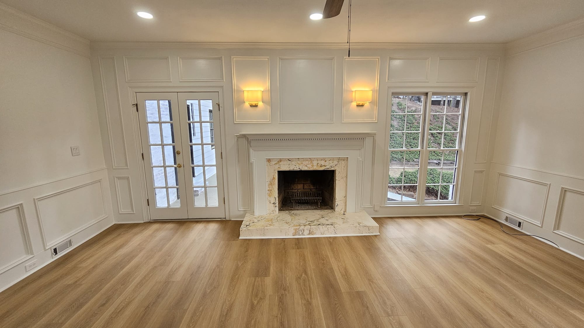 Living room with a white fireplace mantel, marble hearth, and French doors