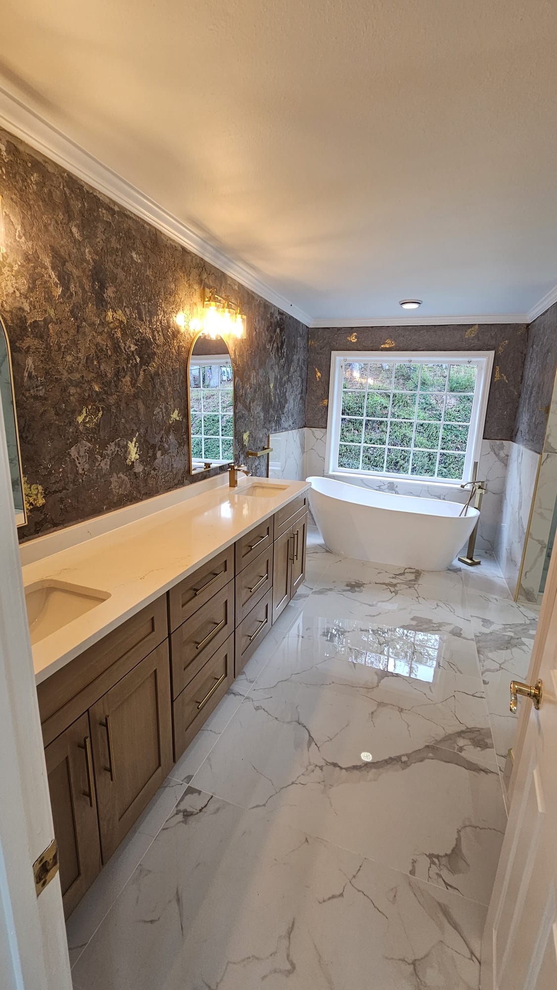 Primary bathroom with freestanding tub, wood vanity, and brass fixtures