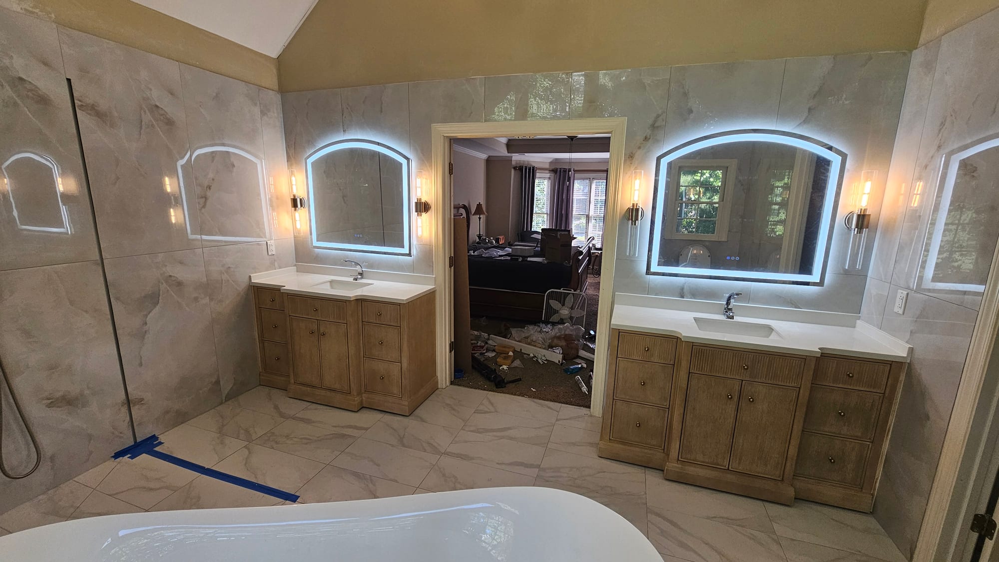 Primary bathroom with dual vanities and backlit arched mirrors, under construction
