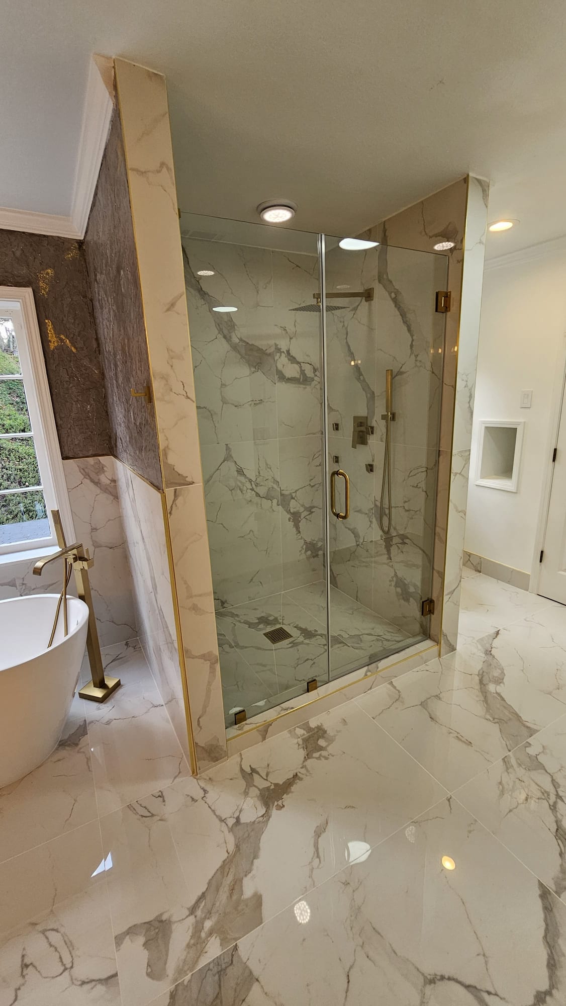 Primary bathroom with a frameless glass shower and brass fixtures