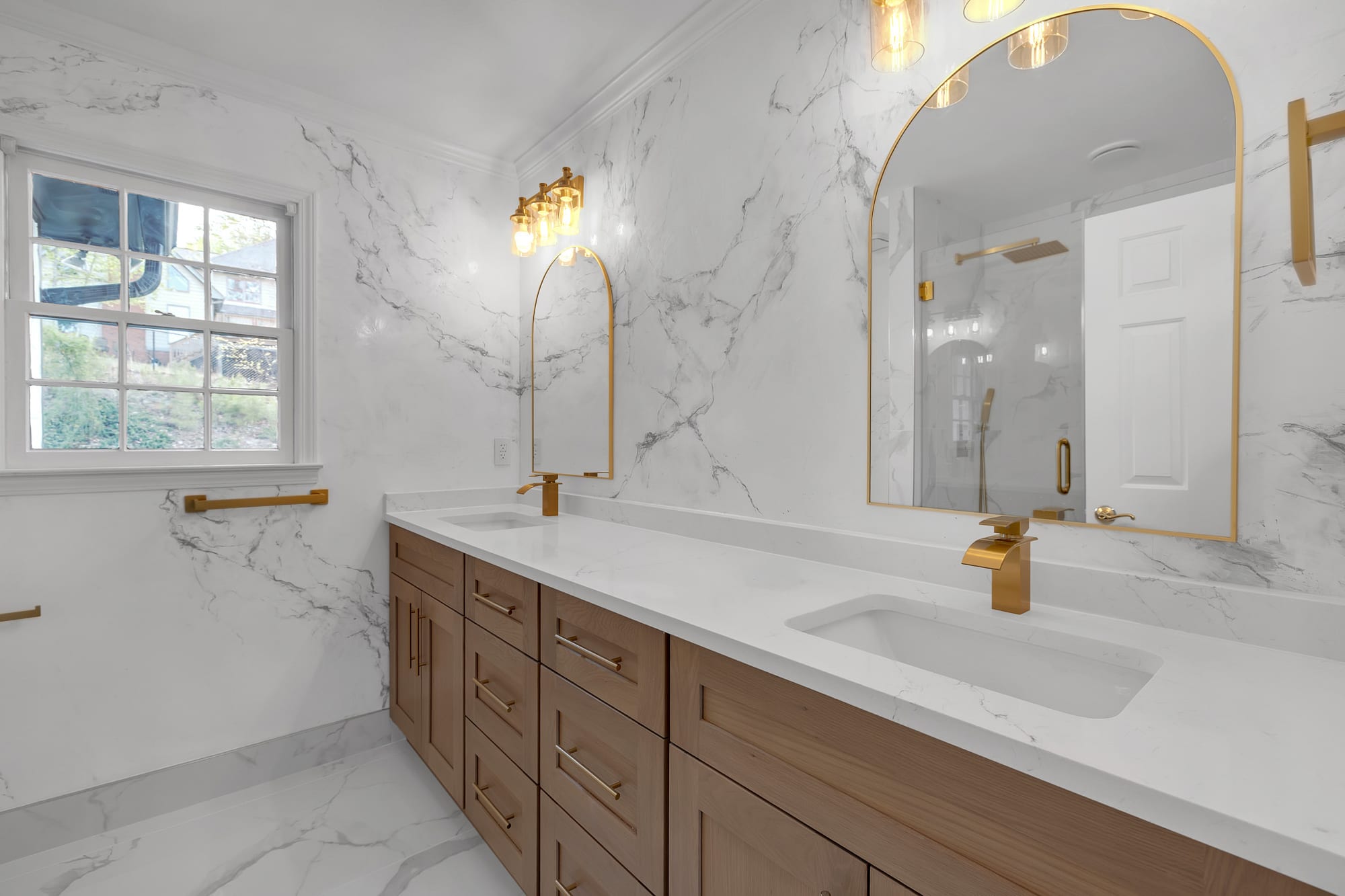 Primary bathroom with a double vanity and arched brass-framed mirrors