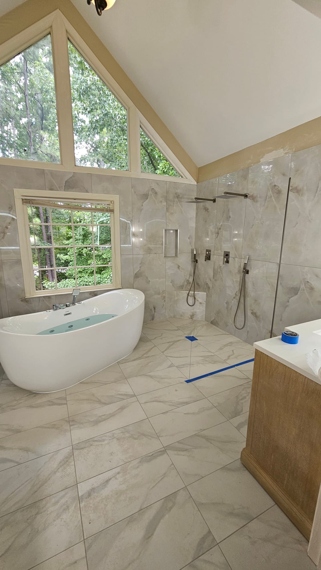 Primary bathroom with marble shower walls, dual shower heads, and a freestanding tub