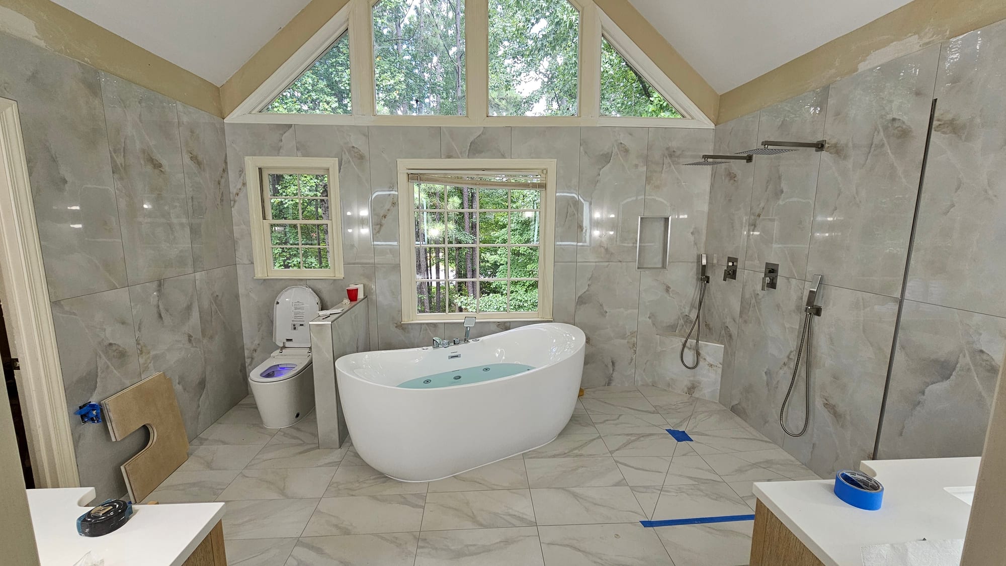 Primary bathroom with marble tile, a smart toilet, and cathedral windows