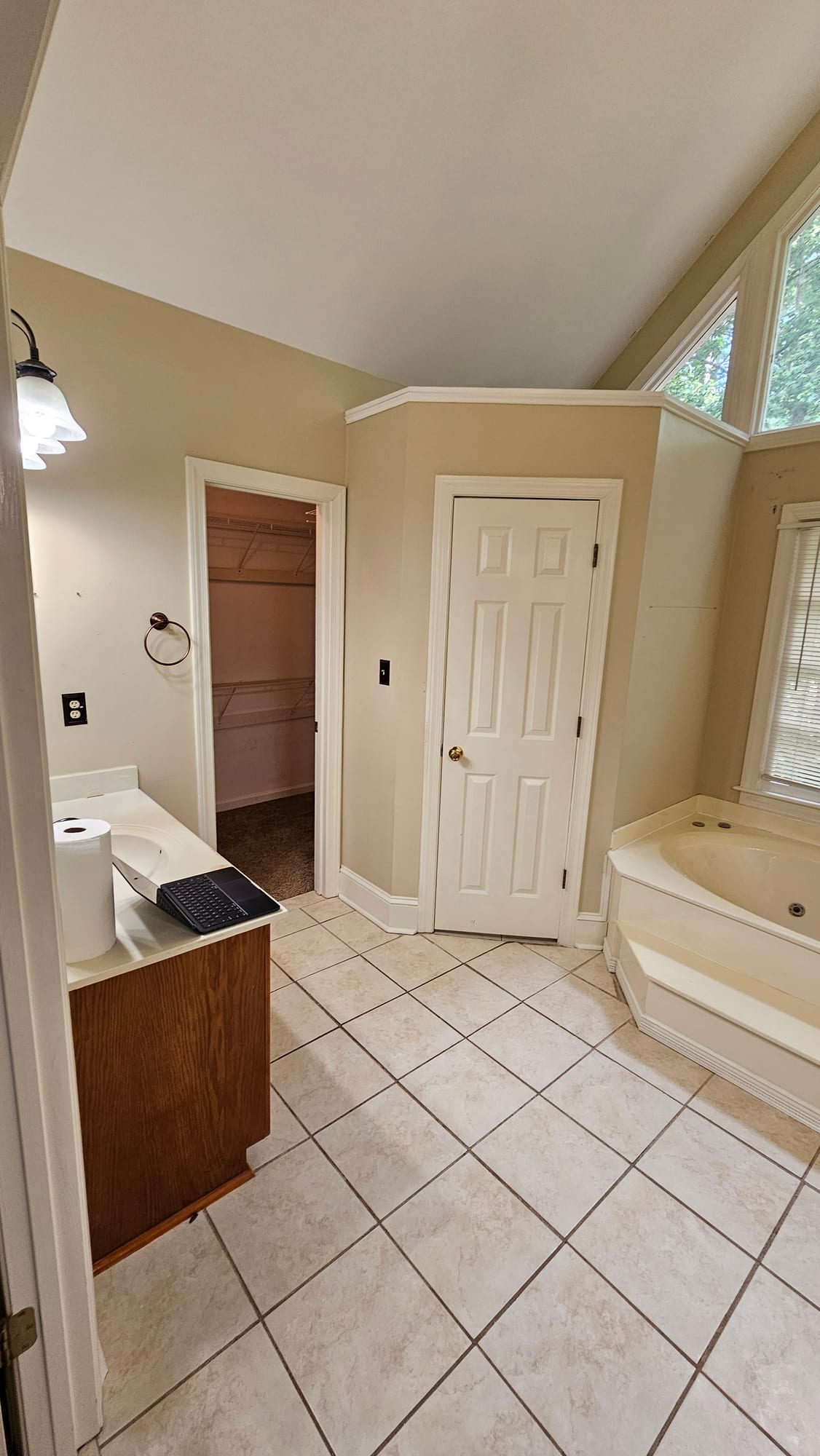 Primary bathroom with an oak paneled door and tile floor, before renovation