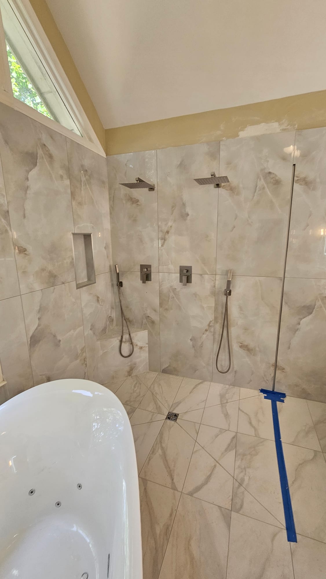 Close-up of shower valve trim set into a marble wall, under construction