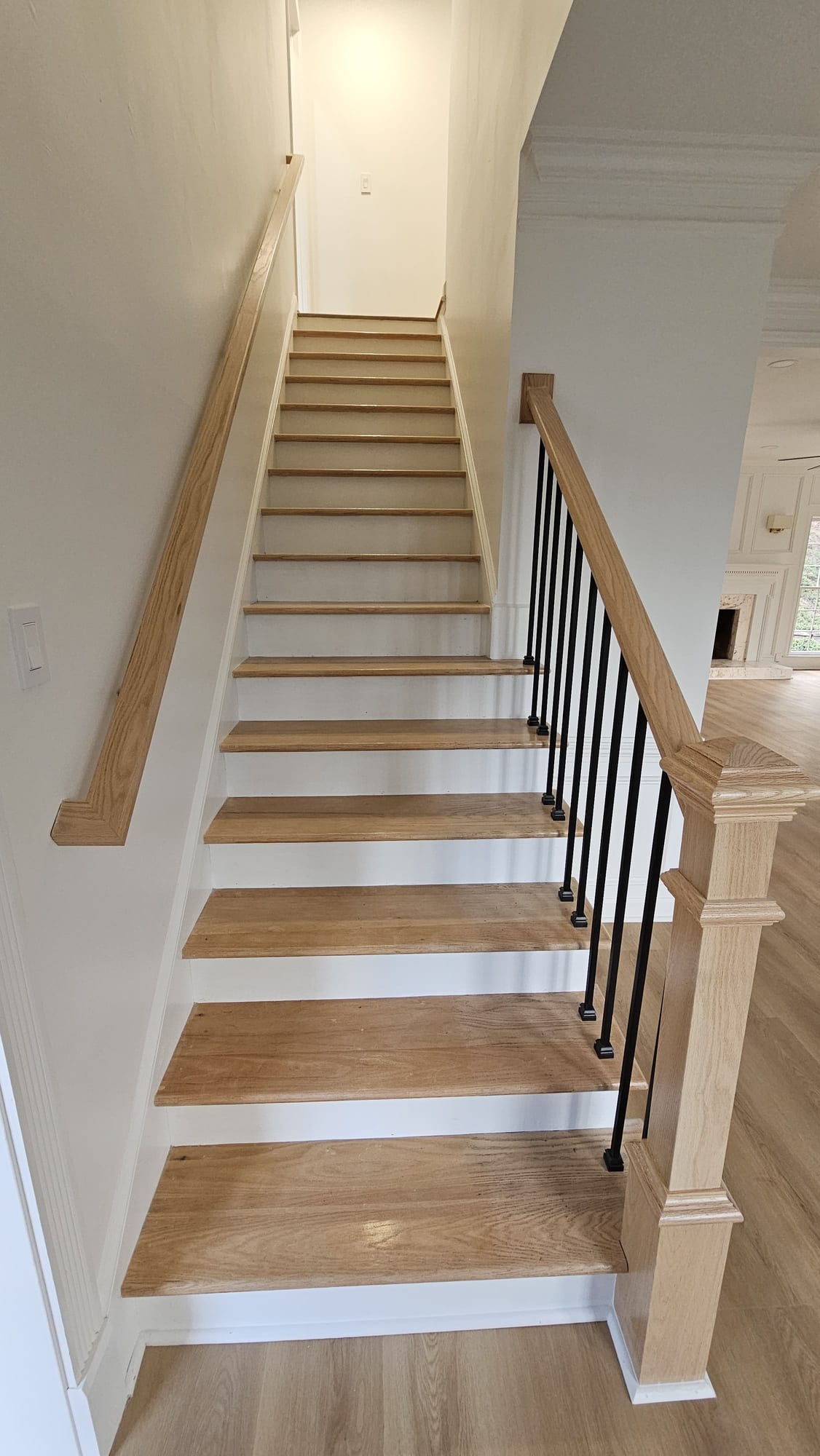 Staircase with white oak treads and a black iron and wood handrail